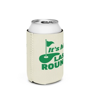 May include: A beige can cooler with a green golf course and flag design. The text "It's the last round" is printed on the cooler.