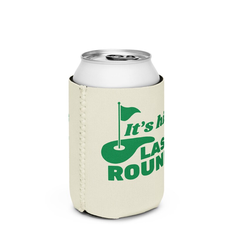 May include: A beige can cooler with a green golf course and flag design. The text "It's the last round" is printed on the cooler.