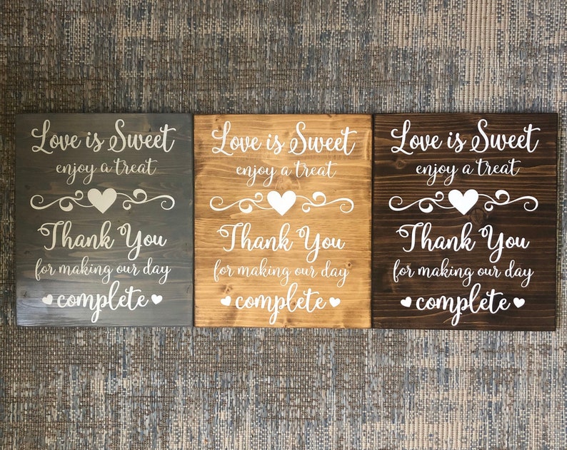 May include: Three wooden signs with the text "Love is Sweet enjoy a treat Thank You for making our day complete" in white lettering on a dark gray, light brown, and dark brown background.