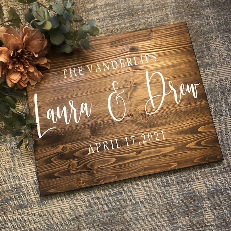 May include: A rustic wooden wedding sign with the text "The Vanderlips Laura & Drew April 17, 2021" in white paint.