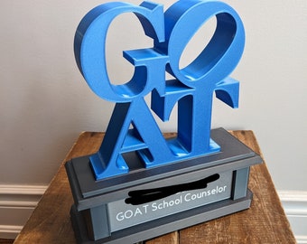 May include: A blue 3D printed trophy with the word "GOAT" on it. The base is black and has the text "GOAT School Counselor" on it.