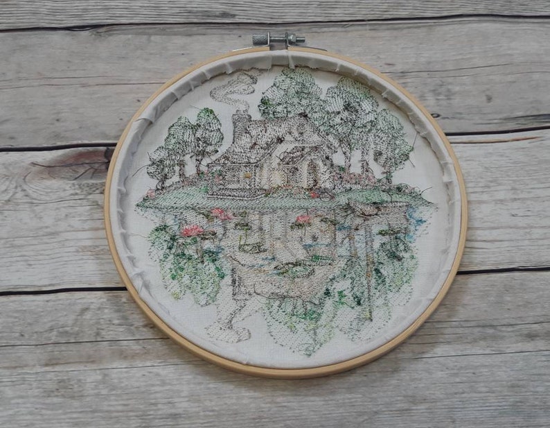 May include: Embroidered hoop art featuring a black and white illustration of a house with trees and flowers. The house is upside down and the trees and flowers are right side up.