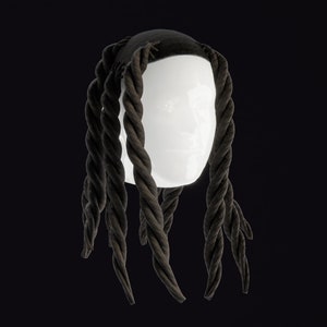 May include: A black wig with long, thick, braided strands. The wig is styled with a centre parting and the braids are twisted and knotted.