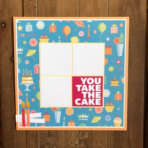May include: A blue and orange scrapbook page with a birthday theme. The page has four photo spaces and the text "YOU TAKE THE CAKE".