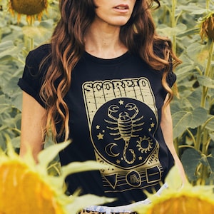 May include: A black t-shirt with a gold graphic of a scorpion and the text "Scorpio" and "Nov 23 - Nov 21".