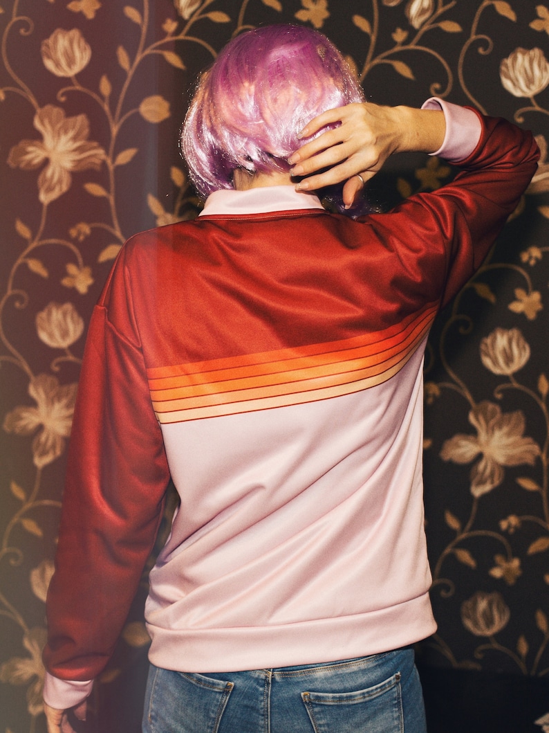 May include: A pink and red striped jacket with long sleeves and a zipper closure. The jacket is made of a soft, smooth fabric.