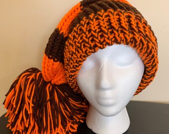 May include: A brown and orange striped knit hat with a long brown and orange tassel.