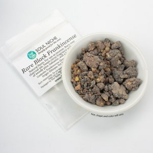 May include: A small white bowl filled with dark gray and amber colored frankincense resin. The bowl is sitting on a white surface. The text on the packaging reads "Soul Niche Simply good for the soul. Rare Black Frankincense Natural Resin. For use as incense. Burn over charcoal tab. Sweet citrus fragrance with of woody pine, balsamic, and a Contents: Frankincense (Boswellia Sacra) Origin: Ethiopia. Net Wt. 1 oz. Burn responsibly. Do not leave unattended. Keep out of reach of children. Packaged by Soul Niche. www.soulniche.com Size, shape and color will vary."