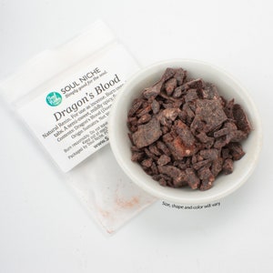 May include: A small white bowl filled with dark red Dragon's Blood resin. The resin is in small, irregular pieces. The bowl is sitting on a white surface. The text on the bag reads "Soul Niche Simply good for the soul. Dragon's Blood Natural Resin. For use as incense. Burn over tabs. A semi-sweet, mildly spicy, floral scent. Contents: Dragon's Blood (Daemonorops draco). Origin Sumatra. Net Weight: 20 g. Burn responsibly. Do not leave unattended. Keep out of reach of children. Packaged by Soul Niche.  www.soulniche.com".