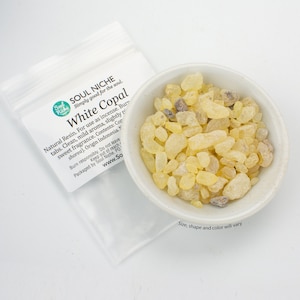 May include: A small white bowl filled with yellow and brown white copal resin pieces. The bowl is sitting on a white surface. The text on the bag reads "Soul Niche Simply good for the soul. White Copal Natural Resin. For use as incense. Burn tabs. Clean, mild aroma, slightly resinous sweet fragrance. Contents: Copal (Shorea). Origin Indonesia.  Burn responsibly. Do not leave unattended. Keep out of reach of children. Packaged by Soul Niche. PO Box 1101,  www.SoulNiche.com"