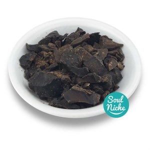 May include: A white ceramic bowl filled with dark brown, irregularly shaped pieces. The pieces have a rough texture and varying shades of brown. The bowl is set against a white background. The image includes a teal circle with the text "Soul Niche".