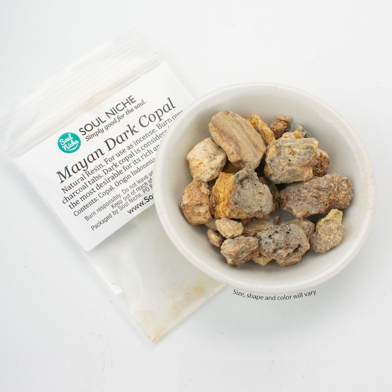May include: A small white bowl filled with Mayan Dark Copal resin pieces. The resin is a natural incense and is considered the most desirable for its rich aroma. The label reads "Soul Niche Simply good for the soul. Mayan Dark Copal Natural Resin. For use as incense. Burn over charcoal tabs. Dark copal is considered the most desirable for its rich aroma. Contents: Copal. Origin Indonesia. Burn responsibly. Do not leave unattended. Keep out of reach of children. Packaged by Soul Niche. PO Box 1000, 94100, Indonesia. www.SoulNiche.com".