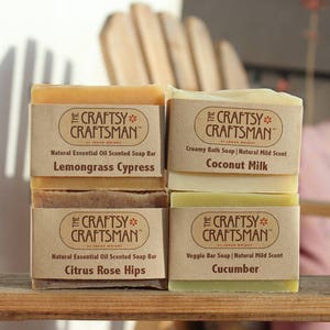 May include: Four bars of natural soap with brown paper labels. The labels have the text "The Craftsy Craftsman" and the scent of each soap bar: Lemongrass Cypress, Coconut Milk, Citrus Rose Hips, and Cucumber.