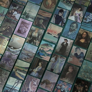 May include: A collection of small, rectangular art prints featuring famous paintings and portraits. The prints are arranged in a grid pattern on a green surface, showcasing a variety of artistic styles and subjects.
