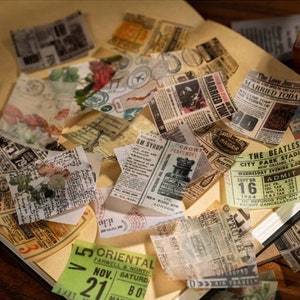 May include: A collection of vintage-style paper ephemera, including newspaper clippings, tickets, and postcards. The papers feature faded colors, floral accents, and various fonts. The items are arranged on a light brown surface, suggesting a scrapbook or craft project.