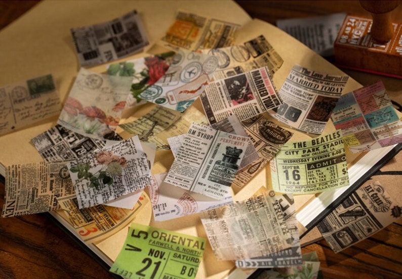 May include: A collection of vintage-style paper ephemera, including newspaper clippings, tickets, and postcards. The papers feature faded colors, floral accents, and various fonts. The items are arranged on a light brown surface, suggesting a scrapbook or craft project.