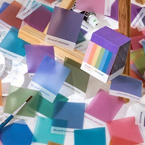 May include: A collection of Morandi color cards in various pastel shades, including pink, blue, and purple. The cards are scattered around art supplies like paint tubes, brushes, and a small bust. The text "Morandi colorcard" is visible on some cards.