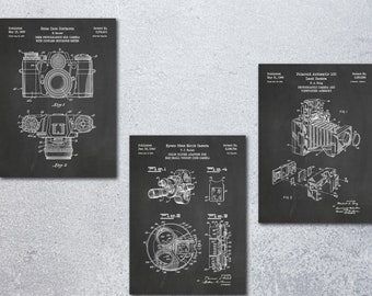 May include: Three vintage camera patent drawings on a chalkboard background. The drawings show a 35mm camera, a Polaroid camera, and a movie camera. The drawings are in black and white and have a vintage look.