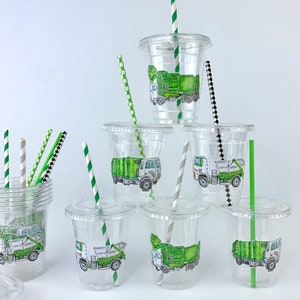Op de afbeelding: Een set van heldere plastic bekers met groene en witte vuilniswagenontwerpen en groen-wit gestreepte rietjes.