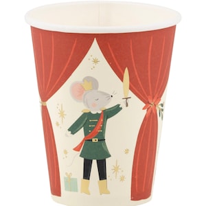 May include: A red and white paper cup with a festive design featuring a mouse dressed as a nutcracker. The mouse is holding a sword and standing in front of a red curtain with gold stars.