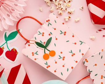 May include: Pink and white striped gift bags with a cherry print and a red ribbon. The bags are decorated with a cherry charm and are perfect for a party or celebration.
