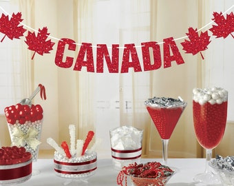 Könnte beinhalten: Rote und weiße Candy-Buffet-Tischdekorationen mit einem roten Glitzer-Banner "CANADA", roten Ahornblatt-Ausschnitten und roten und weißen Bonbons in durchsichtigen Glasbehältern.