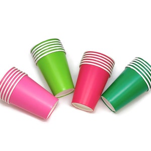 May include: Four stacks of paper cups in green, pink, and a darker green. The cups are stacked on a white background.
