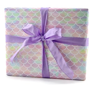 May include: A gift box wrapped in iridescent mermaid scale patterned paper with a large purple satin bow.