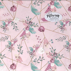 K&ouml;nnte beinhalten: Rosa Geschenkpapier mit einem Blumen- und Federmuster. Das Papier hat geometrische goldene Linien mit Akzenten in Mauve, T&uuml;rkis und Wei&szlig;. Der Text "giftwrap boutique" ist auf der Verpackung zu sehen. Jedes Blatt misst 76 cm x 51 cm.