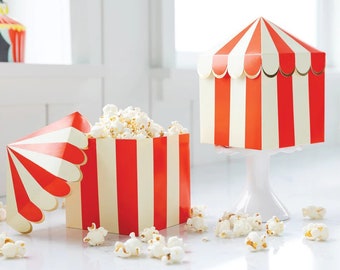 Puede incluir: Cajas de palomitas de maíz rayadas en rojo y blanco con una parte superior en forma de tienda de campaña. Las cajas están llenas de palomitas de maíz y están sobre una superficie blanca.