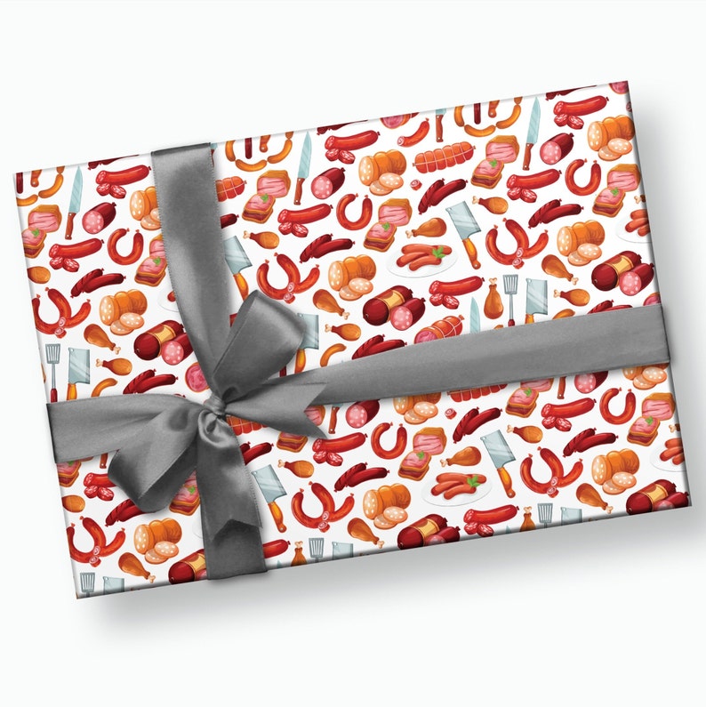May include: A white gift wrapping paper with a repeating pattern of various types of sausages, meat, and kitchen utensils. The paper is tied with a gray ribbon.