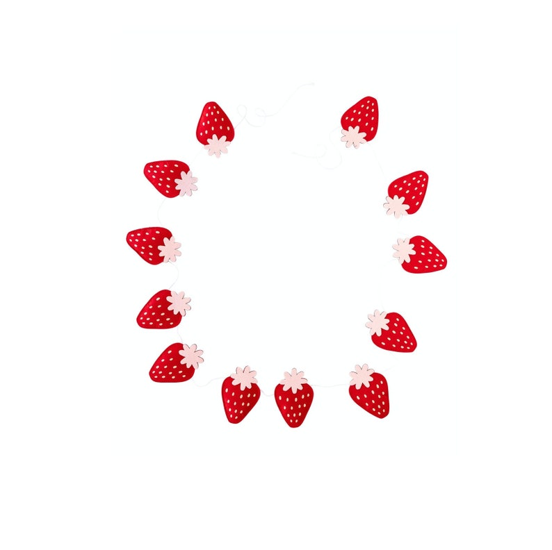 K&ouml;nnte beinhalten: Eine Girlande aus roten und rosa Erdbeeren mit wei&szlig;em Band. Die Girlande ist aus Filz und hat ein schlichtes Design.