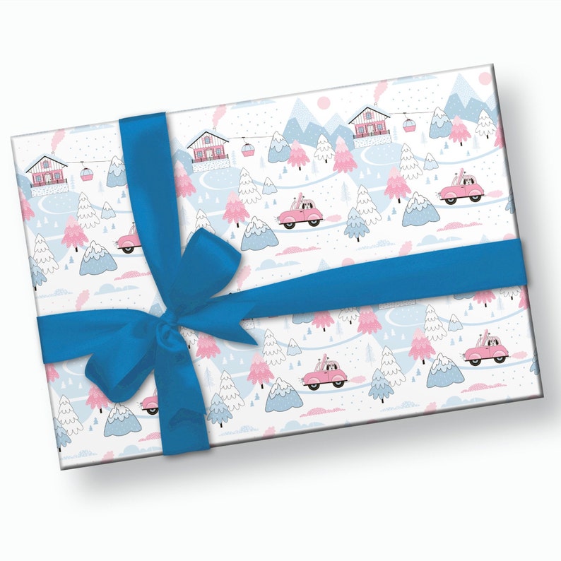 May include: A white gift wrap with a blue ribbon and bow. The wrapping paper features a repeating pattern of pink houses, blue mountains, and pink cars driving through a snowy winter landscape.