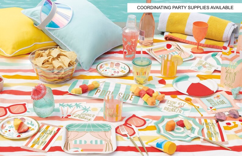 May include: A colorful summer party table setting with a striped tablecloth, paper plates, napkins, and cups with a tropical theme. The table is decorated with a pineapple, sunglasses, and a beach towel. The text on the napkins reads "Low Key Day Drinker", "No Shade", "Vacay All Day", and "Pool Side".