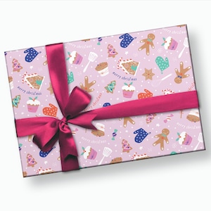 Puede incluir: Papel de regalo rosa con un patr&oacute;n repetido de galletas de jengibre, cupcakes, bastones de caramelo y &aacute;rboles de Navidad. El papel est&aacute; atado con una cinta rosa y un lazo. El texto "merry christmas" aparece varias veces en el papel.