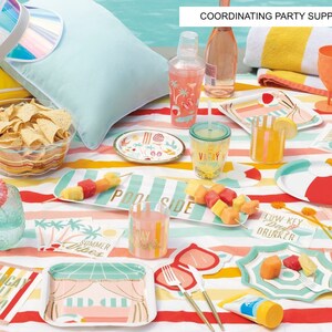 May include: A colorful summer party table setting with a striped tablecloth, paper plates, napkins, and cups with a tropical theme. The table is decorated with a pineapple, sunglasses, and a beach towel. The text on the napkins reads "Low Key Day Drinker", "No Shade", "Vacay All Day", and "Pool Side".