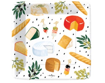 Puede incluir: Plato cuadrado de papel blanco con un patrón repetido de varios quesos, aceitunas, uvas y pan. El plato tiene un patrón de lunares negros.