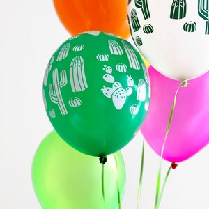 Puede incluir: Cinco globos con un patr&oacute;n de cactus. Los globos son verdes, naranja, blancos, rosas y verde lima.