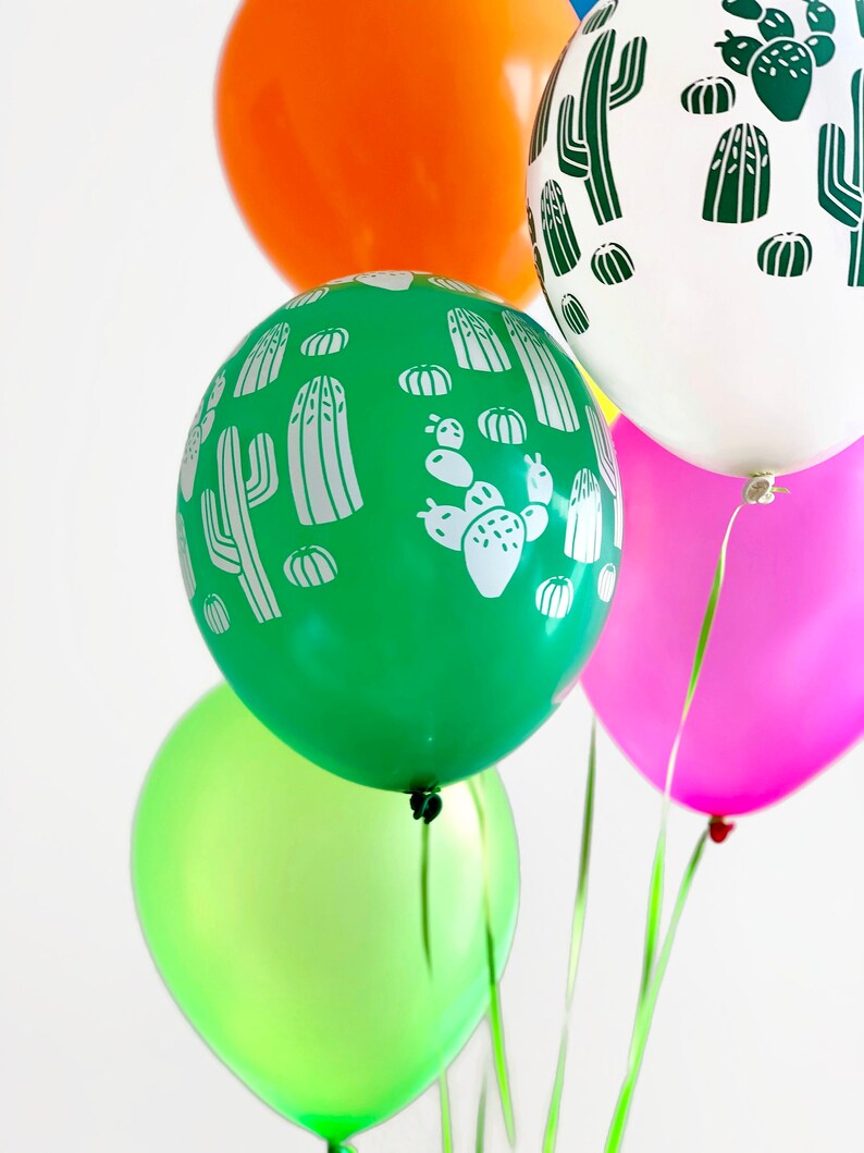 Puede incluir: Cinco globos con un patr&oacute;n de cactus. Los globos son verdes, naranja, blancos, rosas y verde lima.