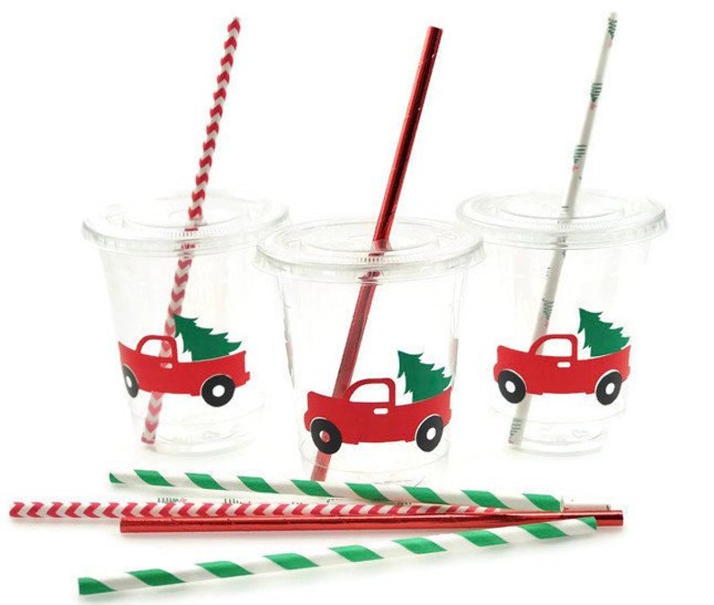 K&ouml;nnte beinhalten: Drei durchsichtige Plastikbecher mit rot-wei&szlig; gestreiften Strohhalmen. Jeder Becher hat einen roten Lastwagen mit einem Weihnachtsbaum hinten drauf. Die Lastwagen sind mit wei&szlig;en Umrissen verziert.