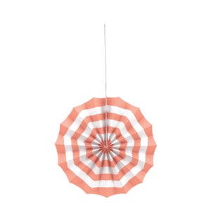 May include: A pink and white striped paper fan decoration hanging from a white string. The fan is folded in a circle shape.