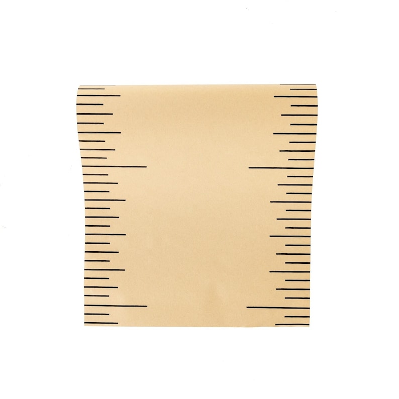 May include: A tan-colored, rolled-up paper ruler with black measurement markings. The ruler has a series of horizontal lines of varying lengths, indicating inches or centimeters. The design is simple and functional, suitable for measuring.
