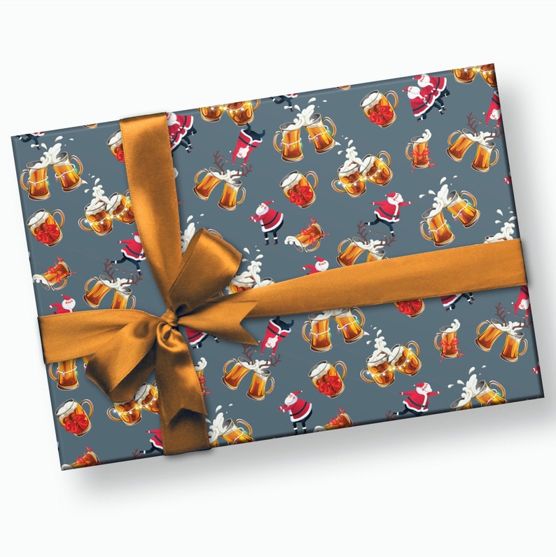 May include: A gray gift box with a festive pattern of Santa Claus figures, beer mugs, and foam. The box is wrapped with a gold ribbon and bow.
