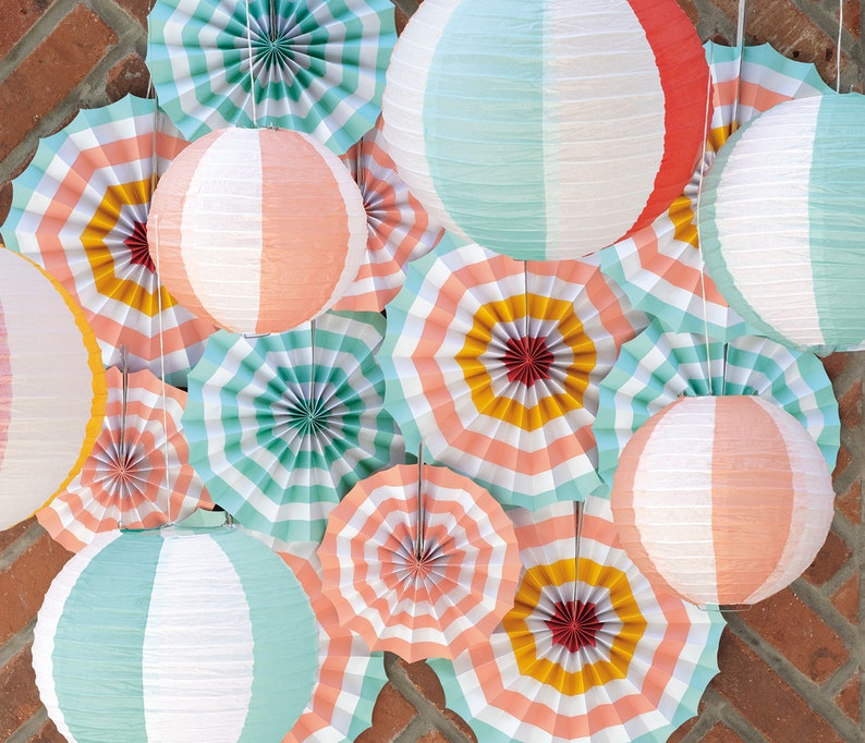 May include: A collection of paper fans and paper lanterns in various colors and patterns, including pink, blue, yellow, and white. The fans are folded and have a striped design, while the lanterns are round and have a striped or solid color design.