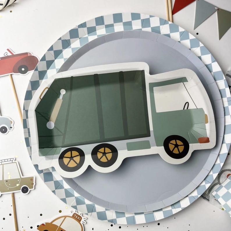 May include: A blue and white checkered paper plate with a green and white garbage truck design. The truck has a yellow cab and black wheels.