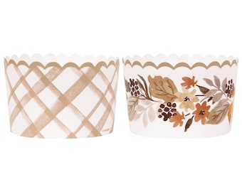 Op de afbeelding: Twee witte cupcakevormpjes met geschulpte randen. Eén heeft een bruin ruitpatroon en de andere heeft een bloemenontwerp met bruine, oranje en beige bladeren en bloemen. Perfect om te bakken.