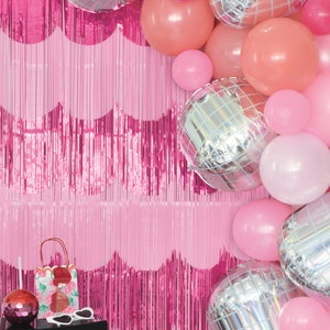 K&ouml;nnte beinhalten: Rosa-silberner Ballonbogen mit rosafarbenem Fransenhintergrund. Die Ballons sind eine Mischung aus einfarbigen rosa, pfirsichfarbenen und silbernen Discokugelballons.
