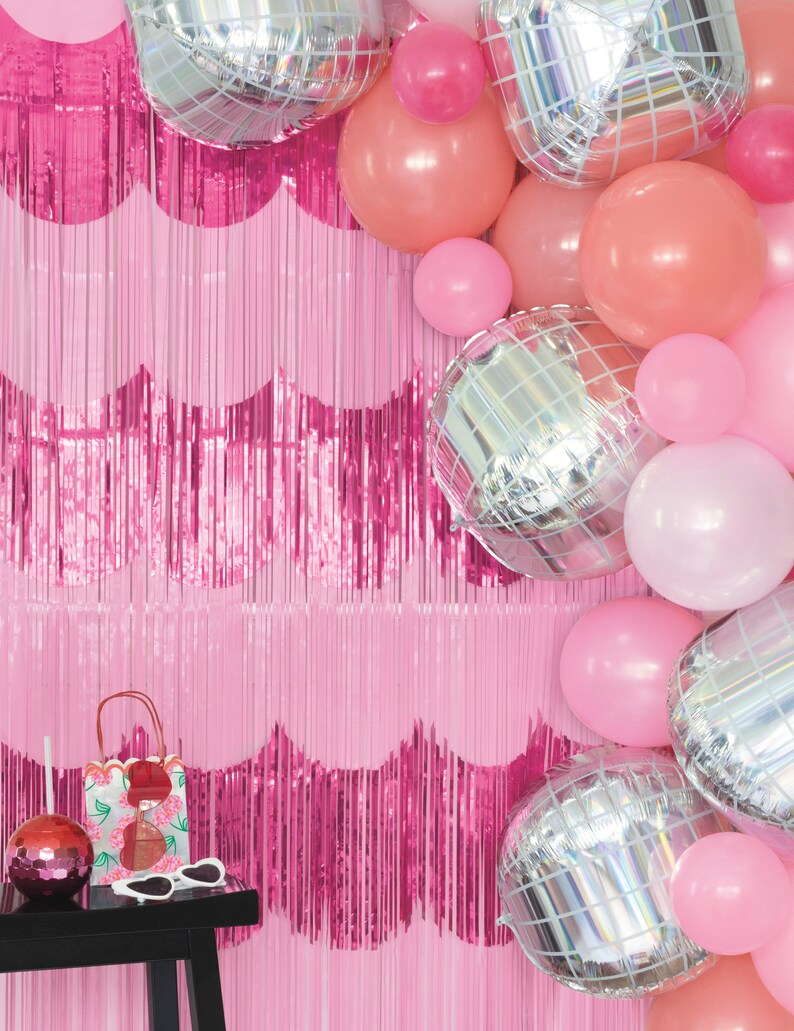 K&ouml;nnte beinhalten: Rosa-silberner Ballonbogen mit rosafarbenem Fransenhintergrund. Die Ballons sind eine Mischung aus einfarbigen rosa, pfirsichfarbenen und silbernen Discokugelballons.