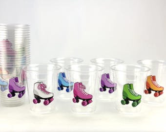 May include: Clear plastic cups with colorful roller skate stickers. The skates are in various colors, including white, pink, purple, blue, green, and orange. A stack of cups is on the left.
