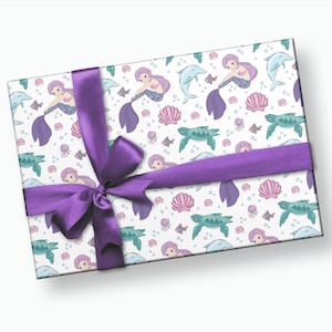 May include: Purple gift wrap with a mermaid, dolphin, turtle, and seashell pattern. The wrapping paper is tied with a purple ribbon.